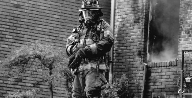 Firefighter suited up walking from a smoky building