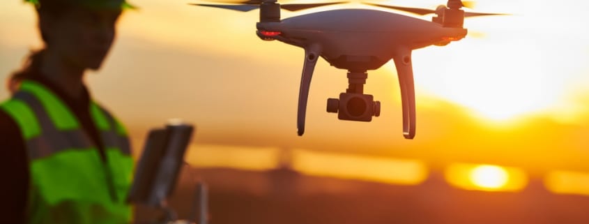 Construction worker operating a drone over a work site