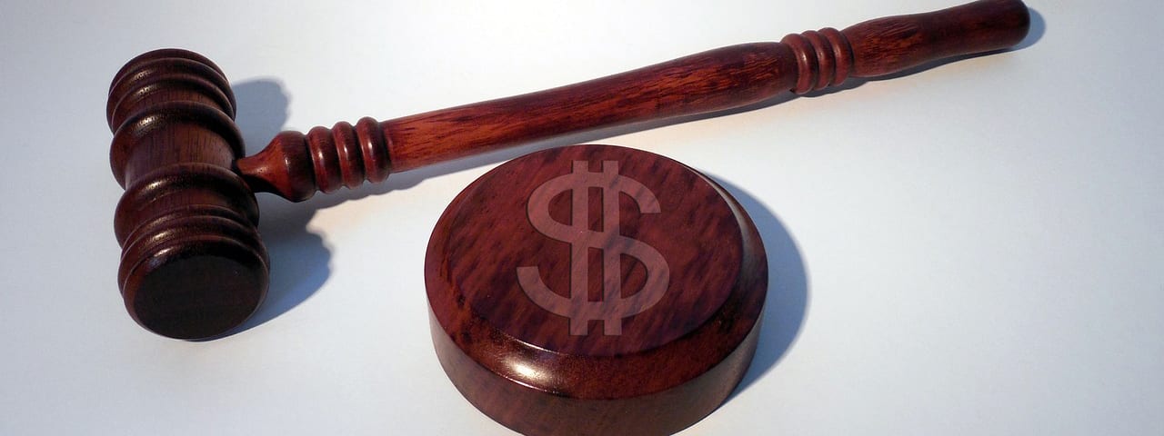 wooden gavel with a money sign symbolizing the losses you could insur without Lawyers Professional Errors and Omissions Insurance