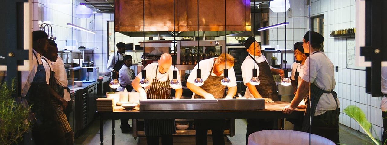 restaurant kitchen with chefs and waitstaff working