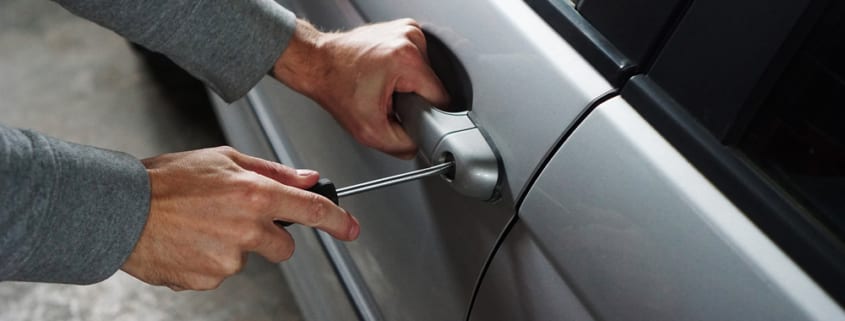 Man trying to break into a car using a screwdriver
