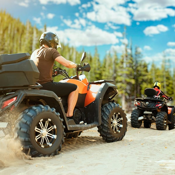 Two quad bike riders in helmets travels in forest