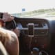 woman driving in car with phone attached to dashboard for hands free driving