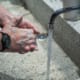 man's soapy hands beside running faucet