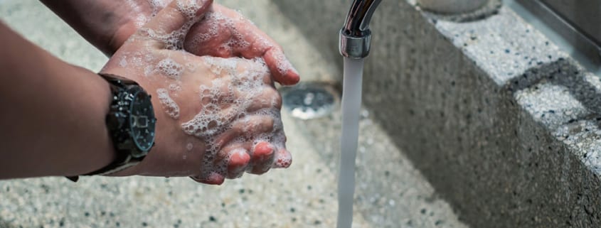 man's soapy hands beside running faucet