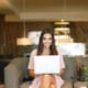 Woman smiling at camera sitting on a couch with a laptop working